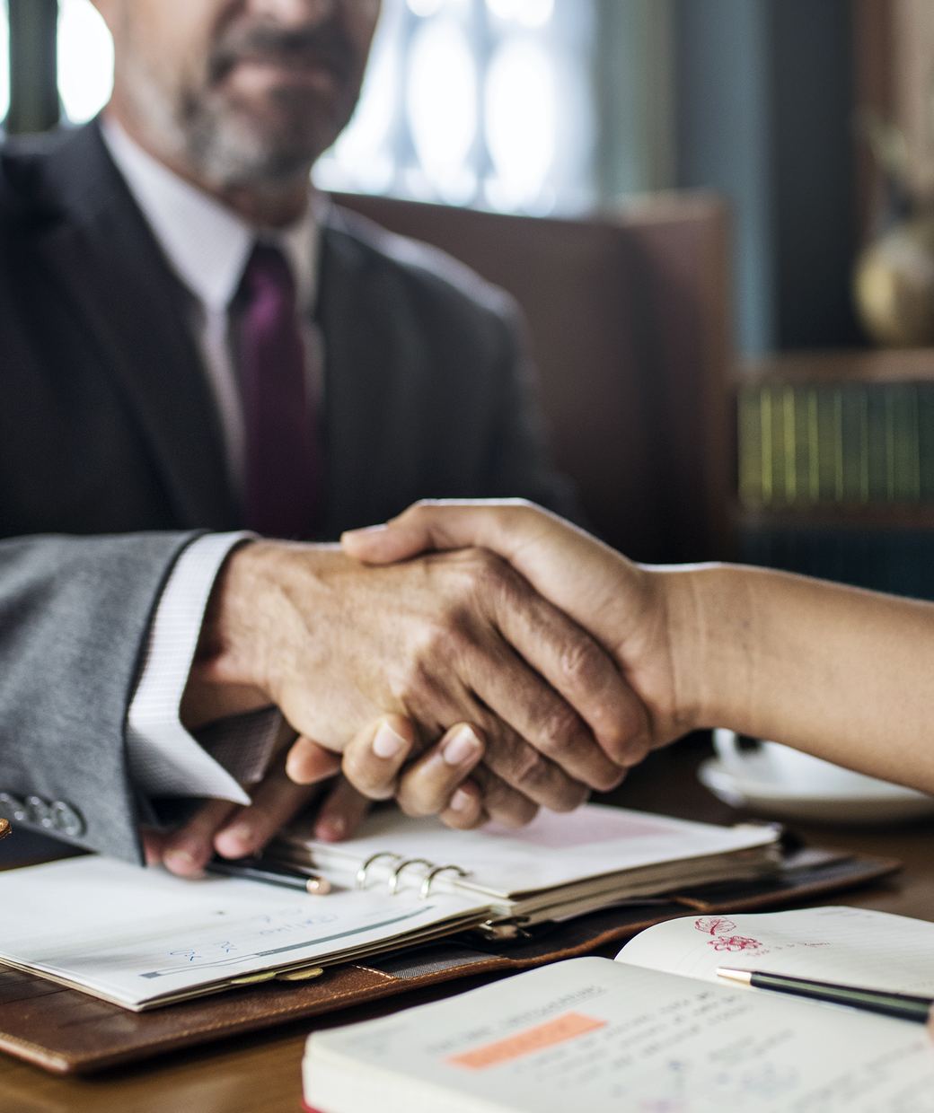An attorney shaking hands with a client across a desk